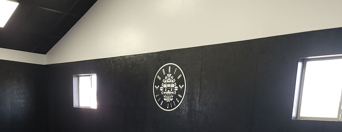 La academia: tatami azul y gris, muro negro y el logo de Ronin.